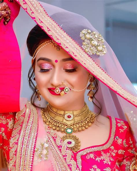 A Woman Wearing A Pink And Gold Bridal Outfit With Jewelry On Her Face