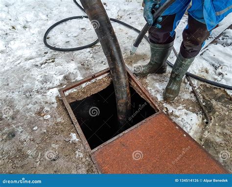 Worker Emptying The Septic Tank With A Sewage Cleaner Machinery Stock