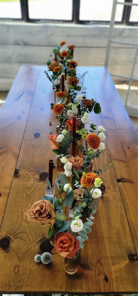 A Long Wooden Table Topped With Lots Of Flowers On Top Of It S Sides