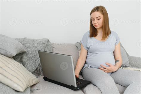 Attractive Pregnant Woman Touching Tummy And Using Laptop On Bed