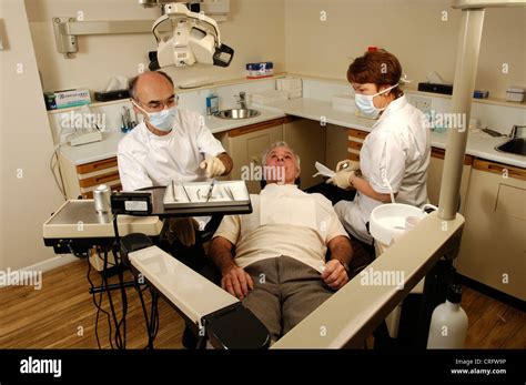 An Elderly Man Lays In The Dentist Chair While The Dentist And His