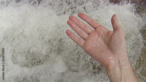 Water Bubbles And Foams At The Base Of A Waterfall As A Mans Hand