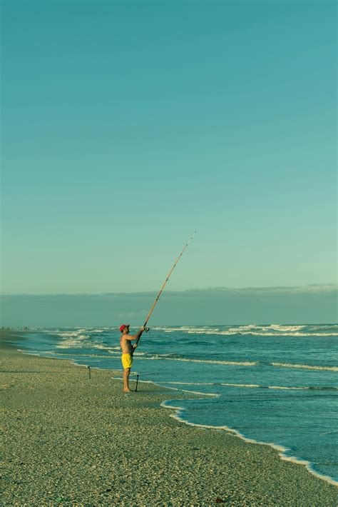 Person Holding Fishing Rod on Beach · Free Stock Photo