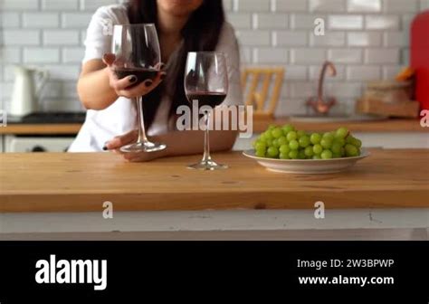 Woman Pours Red Wine Into Glass From Another Glass Close Up Of Woman S