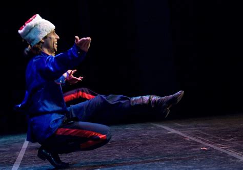 a man sitting on top of a wooden floor next to a person wearing a hat