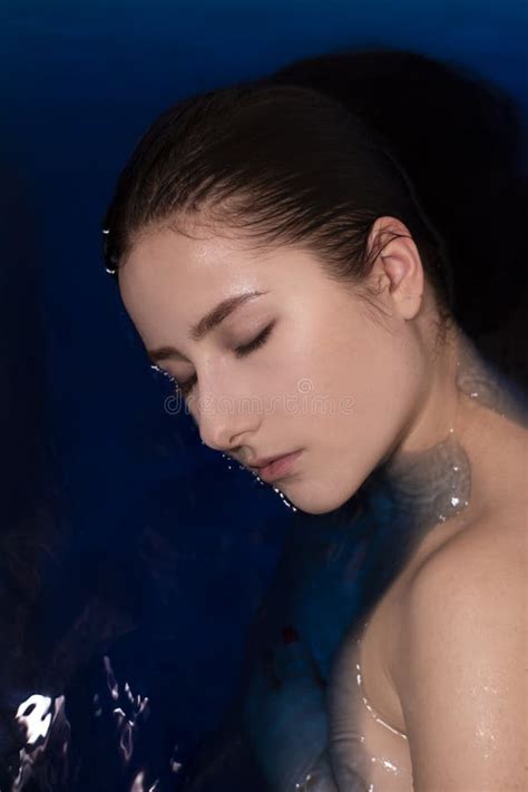 Portrait Of Attractive Brunette Woman Topless In Blue Liquid In Bathtub With Colored Water
