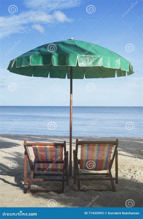 Two Beach Chairs And Umbrella On The Beach With Blue Sky And Blue Sea