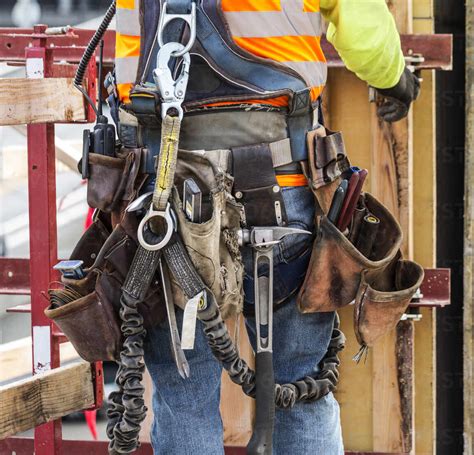 Hispanic Worker Wearing Tool Belt At Construction Site Stock Photo