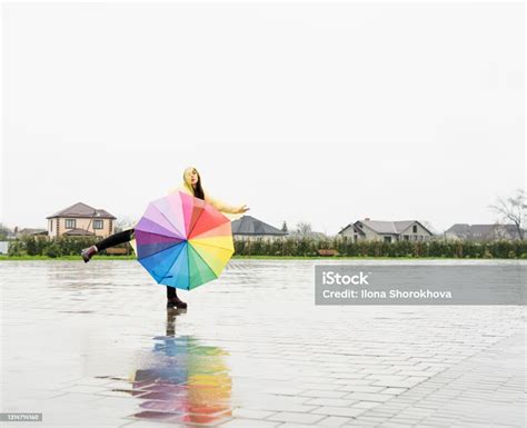 Beautiful Brunette Woman Holding Colorful Umbrella Dancing In The Rain