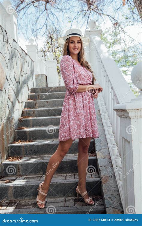 Beautiful Blonde Woman In A Summer Pink Dress On A Walk Around The City