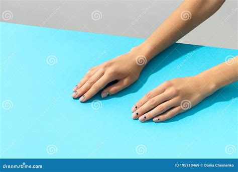 Womans Hands With Nude Nail Design Over Blue Background Stock Image