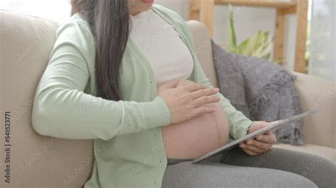 Young Asian Pregnant Woman Hands Fondle On Belly And Using Tablet