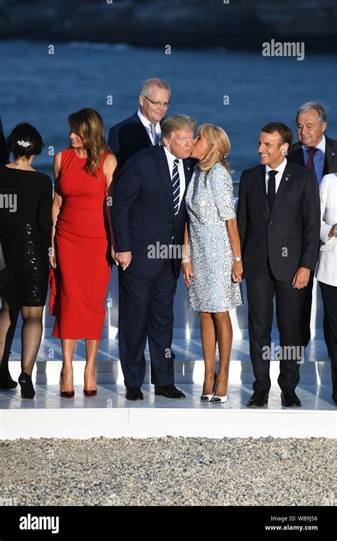 French President Emmanuel Macron watches as his wife Brigitte Macron kisses President Donald ...