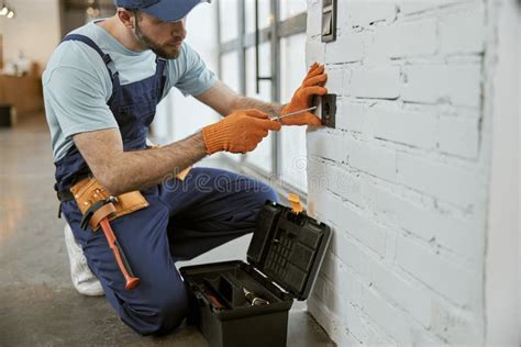 Male Electrician Fixing Electrical Wall Socket With Screwdriver Stock