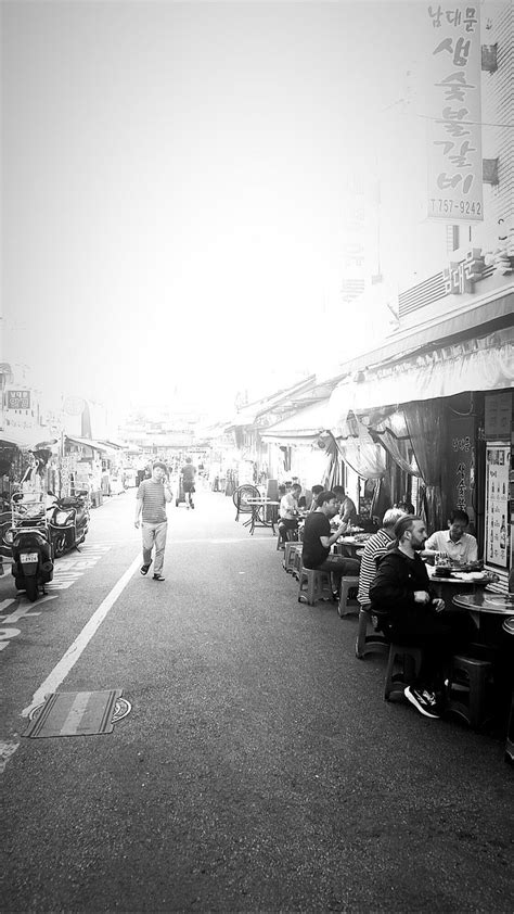 People Are Sitting At Tables On The Side Walk