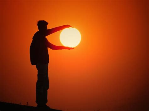 Premium Photo Optical Illusion Of Man Holding Sun Against Clear