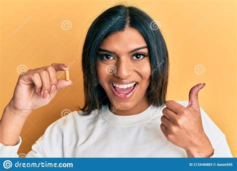 Young Latin Transsexual Transgender Woman Holding Pill Pointing Thumb