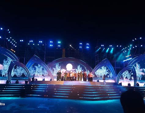 A Group Of People Standing On Top Of A Stage At Night With Bright