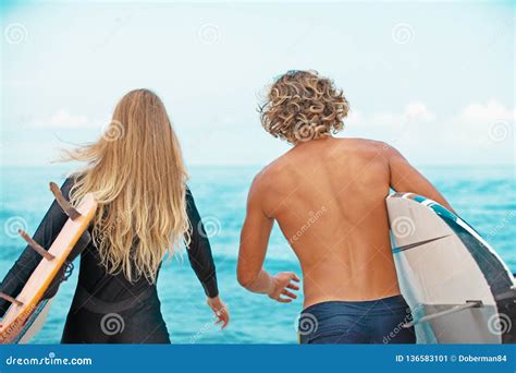 Surfers At The Beach Smiling Couple Of Surfers Walking On The Beach