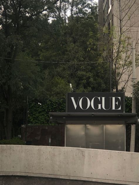 There Is A Sign That Says Voque On The Side Of A Building With Trees In