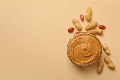 Premium Photo | Peanut and bowl with peanut butter on beige background