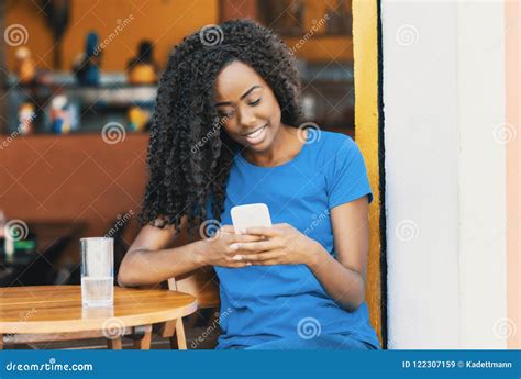 Laughing African American Woman At Bar Texting Message With Mobile