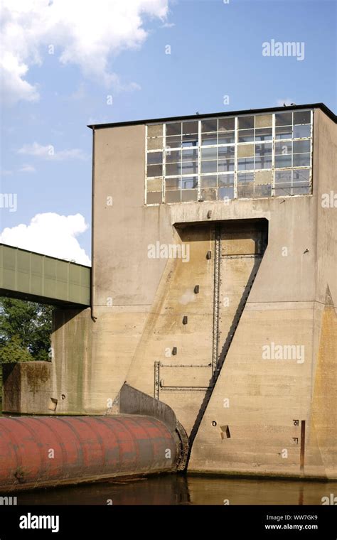 A closed river lock with resting river water and industrial buildings ...