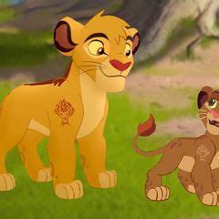 The Lion King And His Cub Are Standing Next To Each Other In An