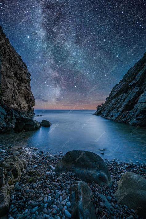 Premium Photo | A night sky with a starry sky and a beach with rocks and a starry sky