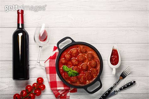 Meatballs In Tomato Sauce In A Frying Pan With Bottle Of Wine Two