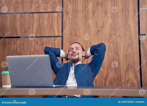 Image Of Businessman With Hands Behind His Head Sitting At Table With