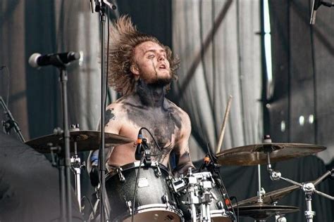 A Man With Tattoos On His Chest Playing The Drums At A Music Festival