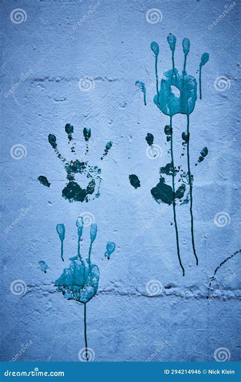 Blue Handprints On Muscular Naked Body Of Male Fitness Model Kneeling On Floor With Black