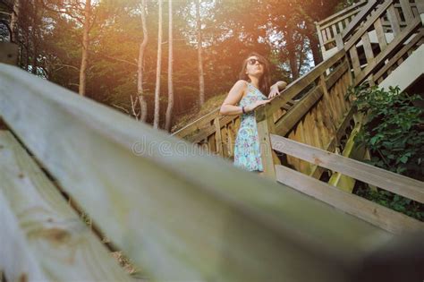 Menina Que Senta Se Nas Escadas De Madeira No Parque E No Sorriso