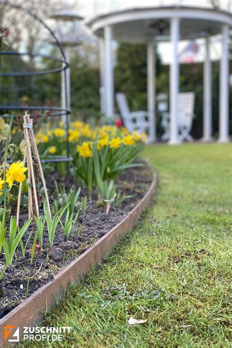 A Garden With Yellow Flowers And Green Grass In Front Of A Gazebo On A