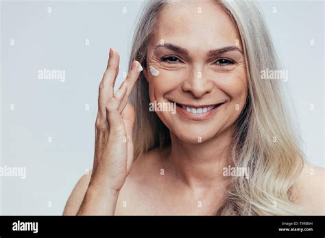 Smiling Mid Adult Caucasian Woman Applying Anti Aging Cream On Her Face