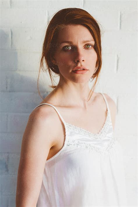 Portrait Of Red Hair Woman In Front Of White Brick Wall By Stocksy