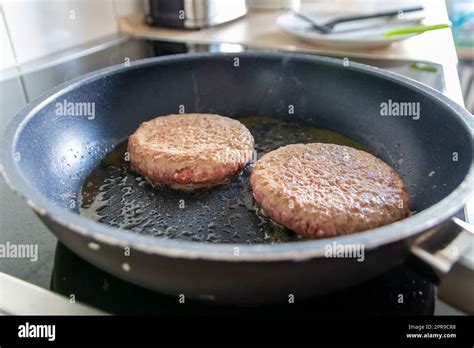 Zwei Burgerpasteten Burgerfleisch brutzelt in einer heißen Pfanne mit