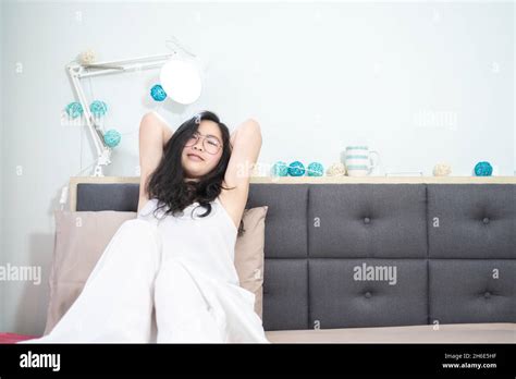 Asian Young Glasses Woman Stretches Oneself On Her Bed In The Morning