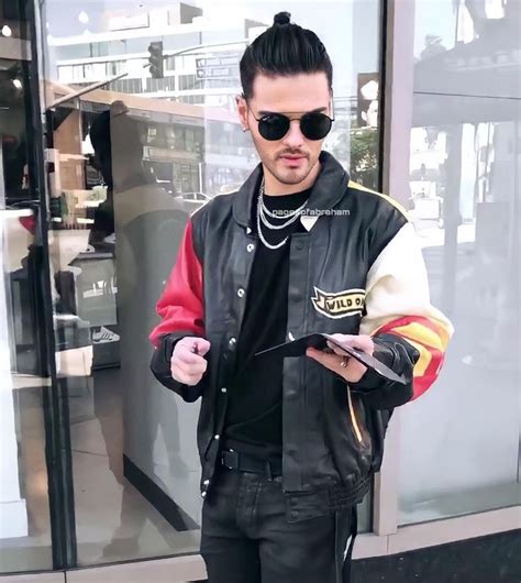 A Man In Black Leather Jacket And Sunglasses Holding A Cell Phone While