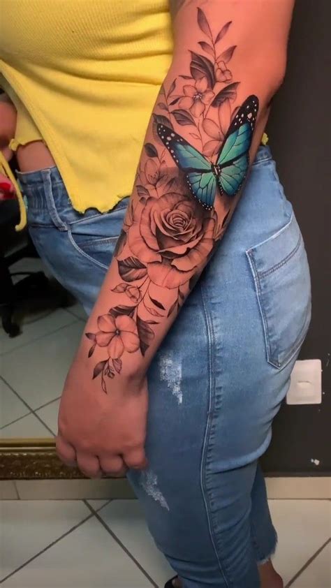 A Woman With A Butterfly And Flowers Tattoo On Her Arm Is Standing In