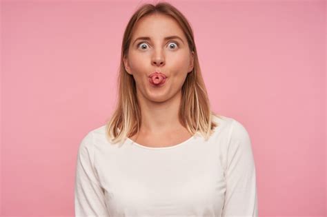 Jolie Jeune Femme Blonde Positive Avec Une Coiffure Décontractée Se Moquant Sur Fond Rose