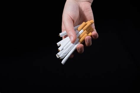 Premium Photo Cropped Hand Holding Cigarettes Over Black Background