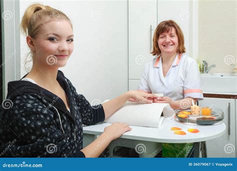 Beautician With File Filing Nails Female Client In Beauty Salon Stock