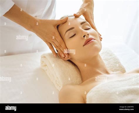 Beautiful Woman Enjoying Facial Massage With Closed Eyes In Spa Center