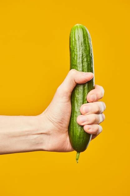 Premium Photo Vibrant Shot Of Hand Holding Cucumber On Yellow