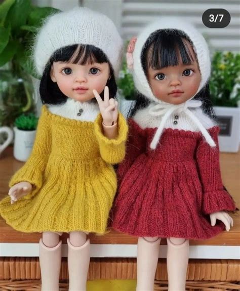 Two Dolls Standing Next To Each Other On A Table