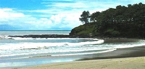 A Sandy Beach Next To The Ocean Under A Blue Sky With White Clouds And