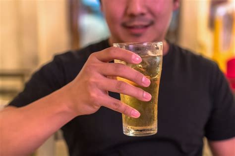 Premium Photo Closeup Hand Holding Glass Of Beer From Asian Young Man