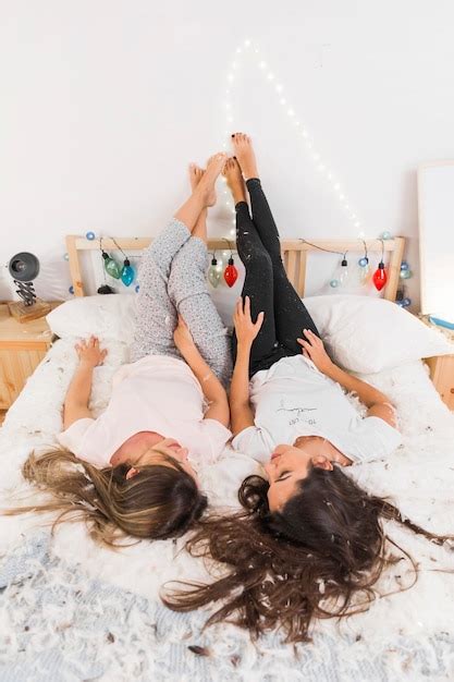 Free Photo Female Friends Lying On Messy Bed With Her Legs Up Leaning